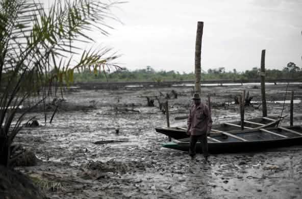 Un uomo si trova nel letto di un fiume inquinato dal petrolio nel Delta del Niger.