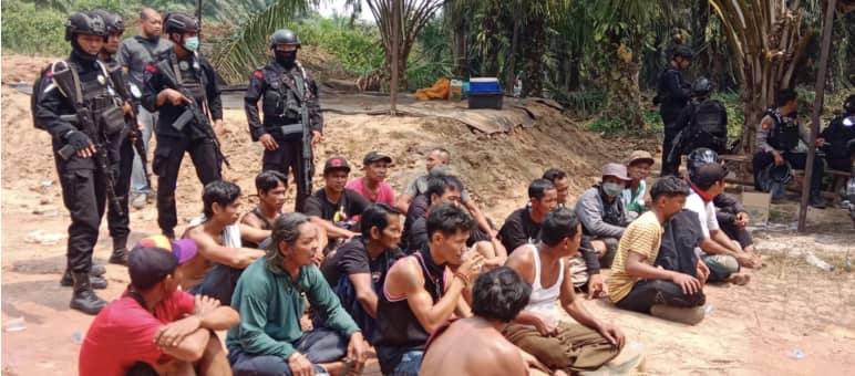 La resistenza all'accaparramento della terra per l'olio di palma causa spargimento di sangue o porta al carcere: indigeni Dayak arrestati nella piantagione della Best Group Indigeni Dayak arrestati siedono a terra con la polizia armata alle spalle.