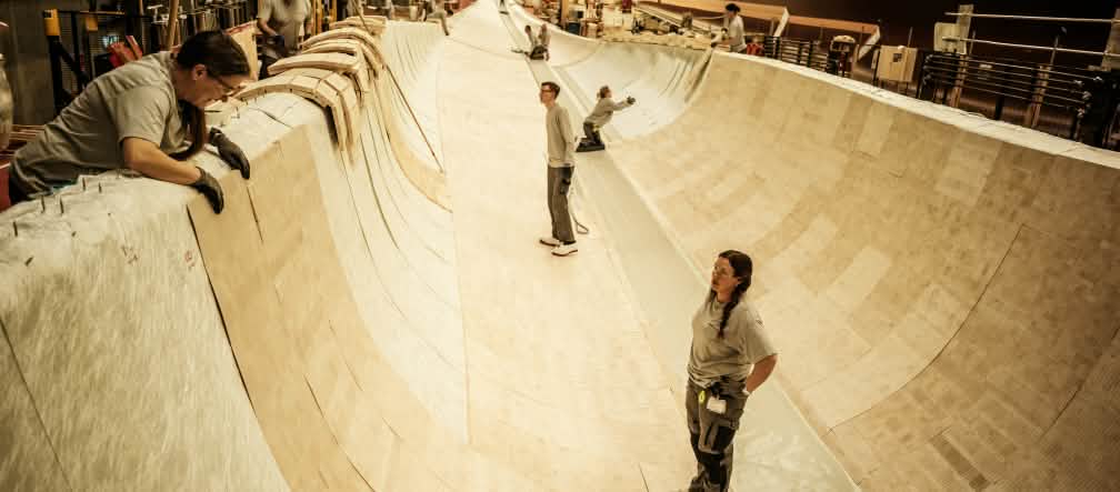 Il legno di balsa viene utilizzato come materiale di rinforzo in una pala di rotore lunga 81 metri in uno stabilimento Siemens Gamesa in Danimarca nel febbraio 2022. Diverse persone si trovano all'interno del rivestimento in legno di balsa per la costruzione della pala di un rotore.