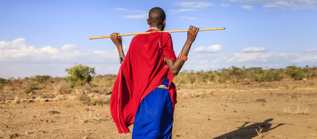 I pastori Masai hanno contribuito con il loro stile di vita alla conservazione del cratere di Ngorongoro Persona Masai di spalle, con in mano un bastone di legno.
