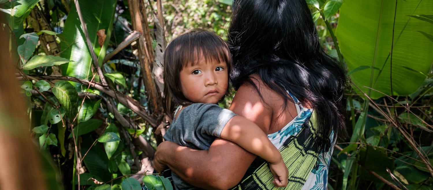 Donna indigena Ka'apor nella vegetazione della foresta amazzonica con il suo bambino in braccio.