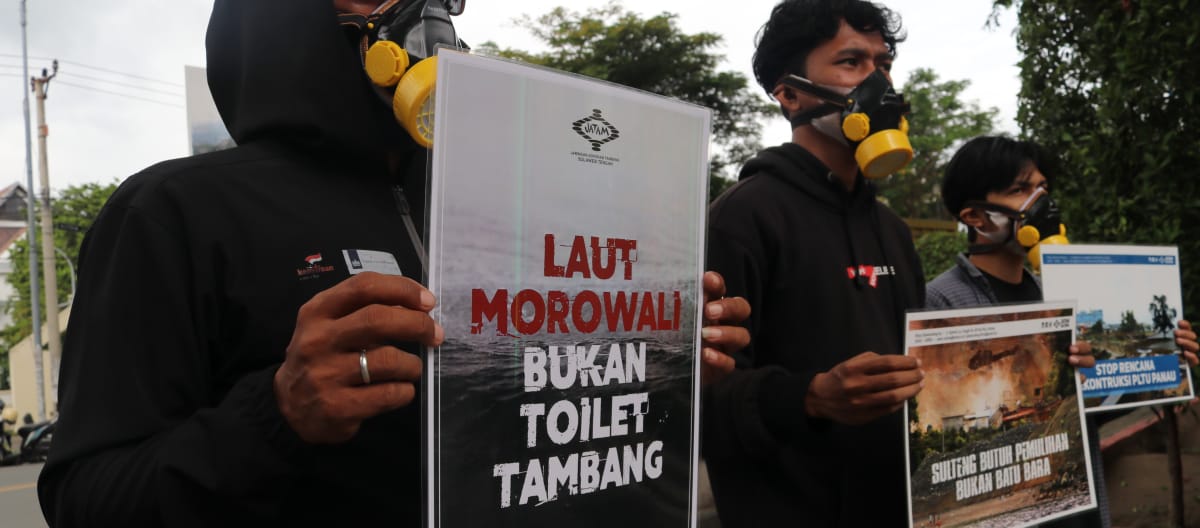 Tre attivisti di Jatam con striscioni di protesta che recitano in indonesiano “Il mare di Morowali non è un gabinetto per le miniere”.