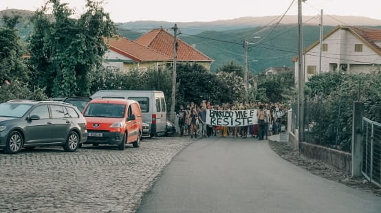 I partecipanti all'accampamento Barroso senza miniere a Covas do Barroso, in Portogallo, manifestano per le strade del villaggio con uno striscione che recita “Barroso vive e resiste”.