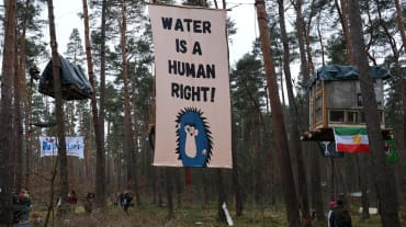 Striscione con la scritta in inglese "Water is a Human Right" (L'acqua è un diritto umano) appeso agli alberi dell'accampamento contro l'espansione della megafabbrica di Tesla a Grünheide.