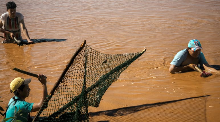 Tre persone pescano con reti tradizionali sul fiume Pilcomayo, in Paraguay.