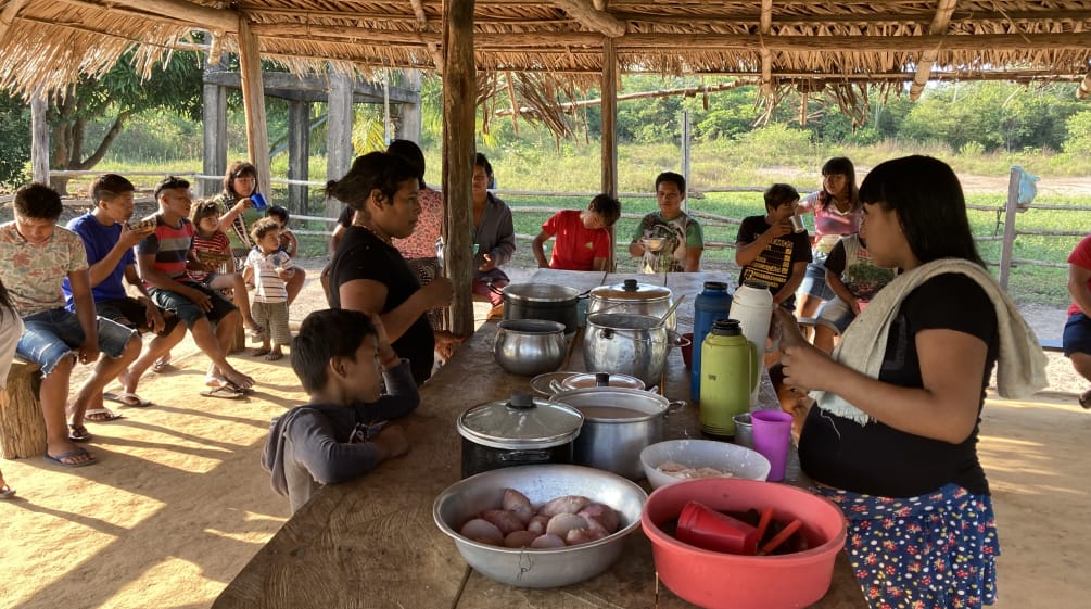 Donne, bambini e adolescenti indigeni durante un pasto comune in un'oca aperta