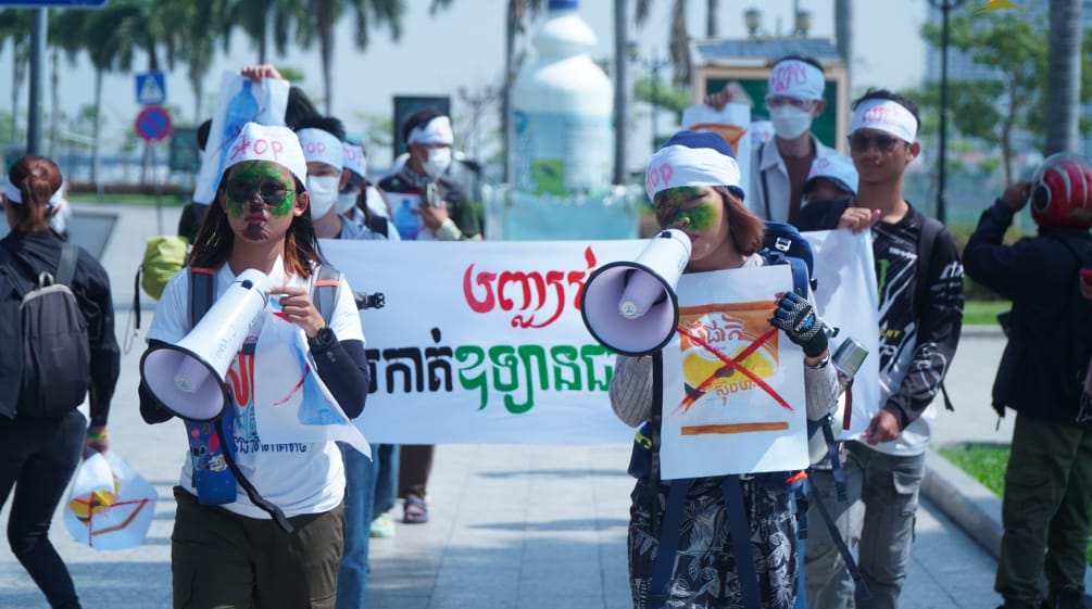 Un gruppo di giovani studenti attraversa una strada con megafoni e cartelli.